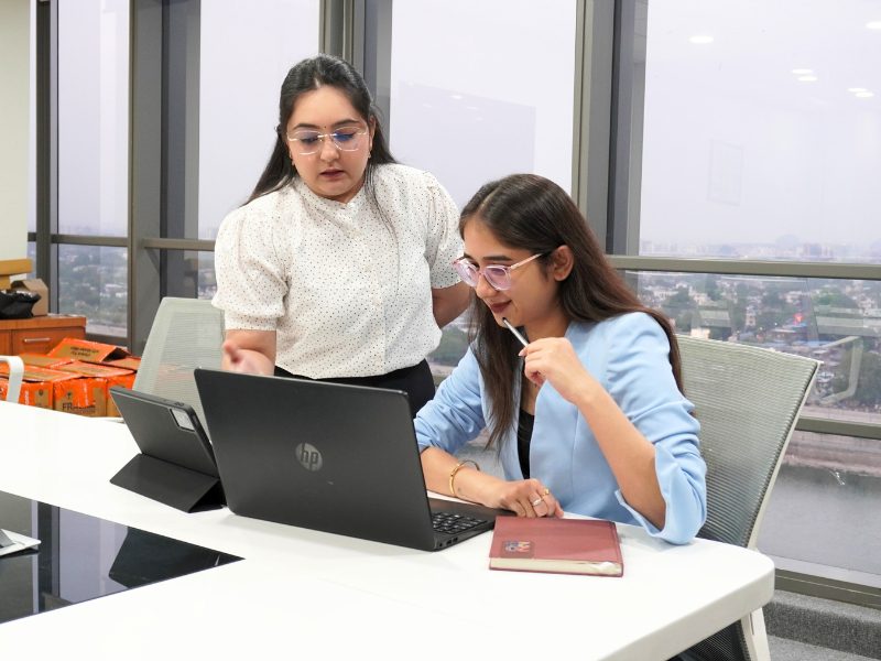 Two female professionals collaborating on HP laptop in iConsultera Ahmedabad office